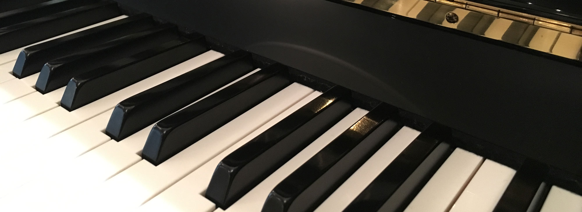 Ein Detailaufnahme eines Klaviers. Man erkennt nur die weißen und schwarzen Tasten.