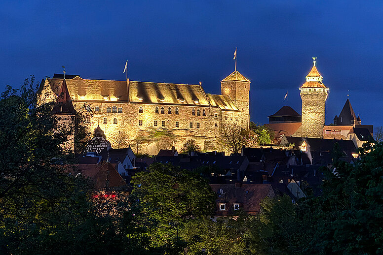 Eine Nachtaufnahme der Nürnberger Burg. Die Burg ist stimmungsvoll beleuchtet.