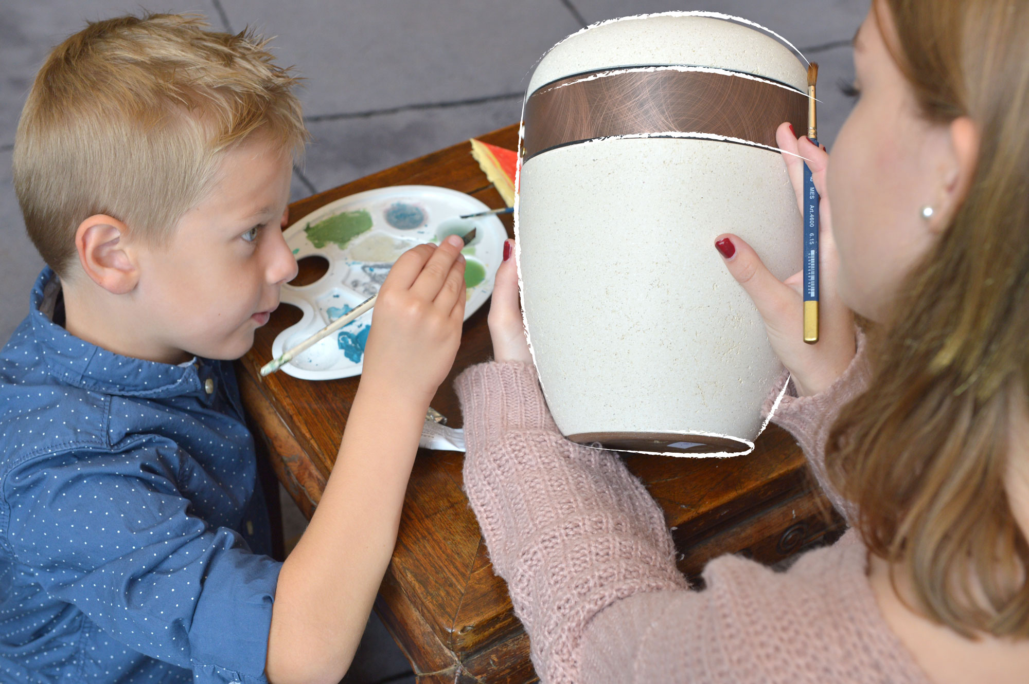 Kinder bemalen die Urne eines Verstorbenen mit bunten Farben.