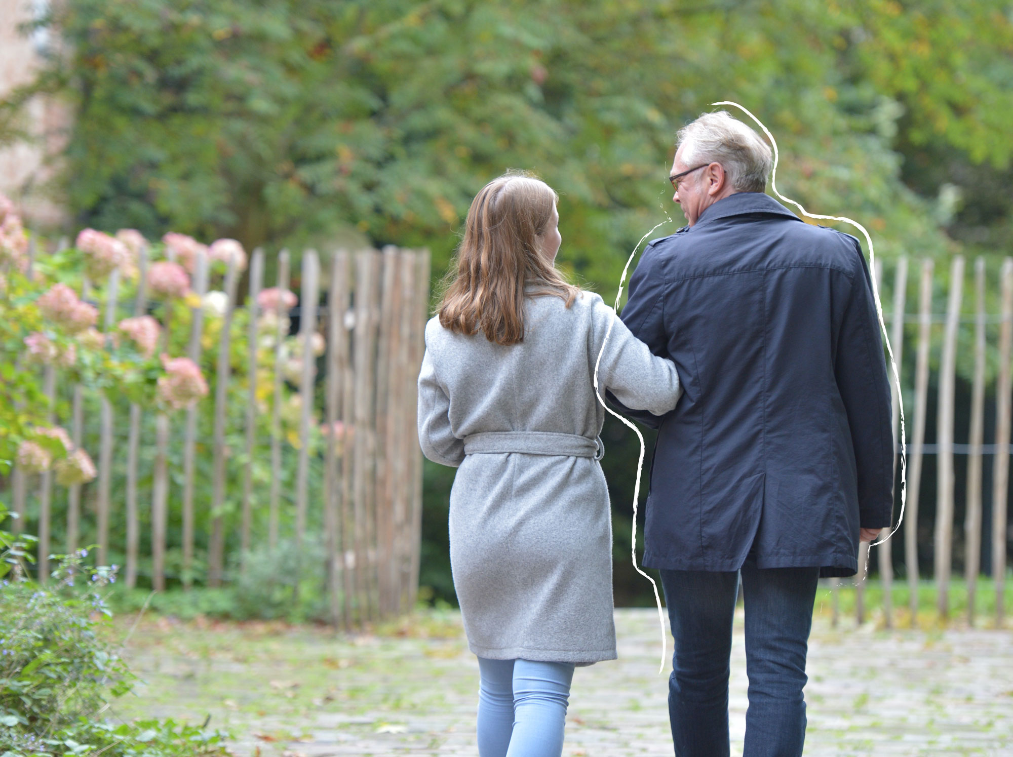 Eine Frau hat sich bei einem Mann mit ihrem Arm untergehakt und sie gehen spazieren.